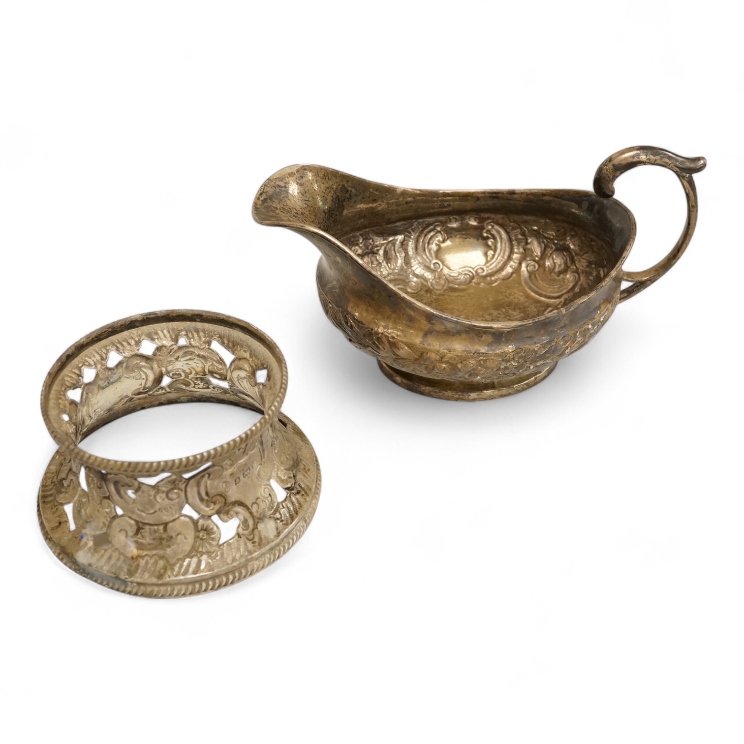 A late George III Irish embossed silver sauce boat, with flying scroll handle, maker. ?S, Dublin, 1817, length 14cm, together with a small Edwardian silver dish ring, I S Greenberg & Co, Birmingham, 1901, 7.2oz.